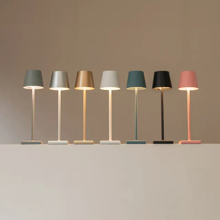 Seven table lamps with different colored shades on a neutral background