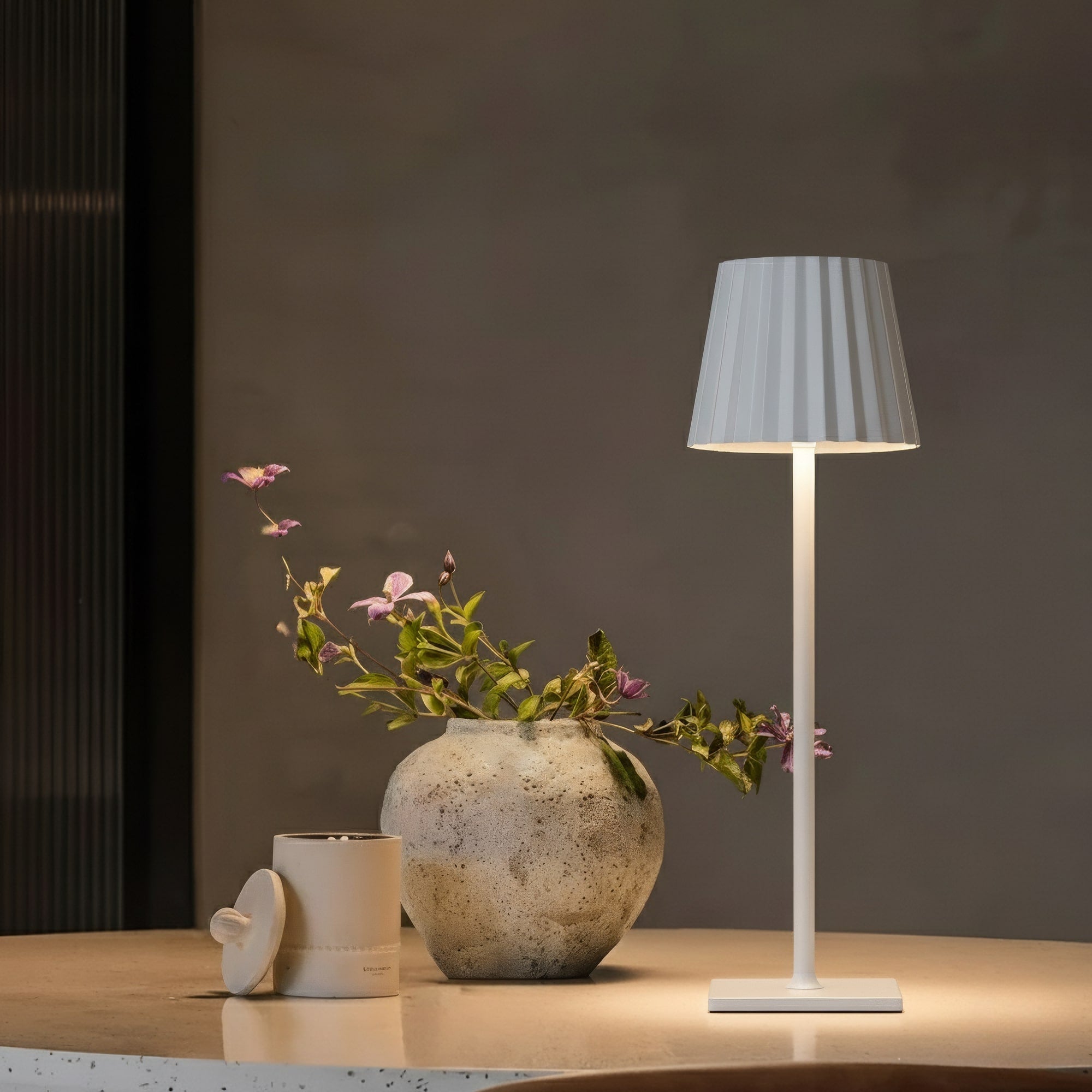 Table lamp with gray shade and floral arrangement on a wooden surface